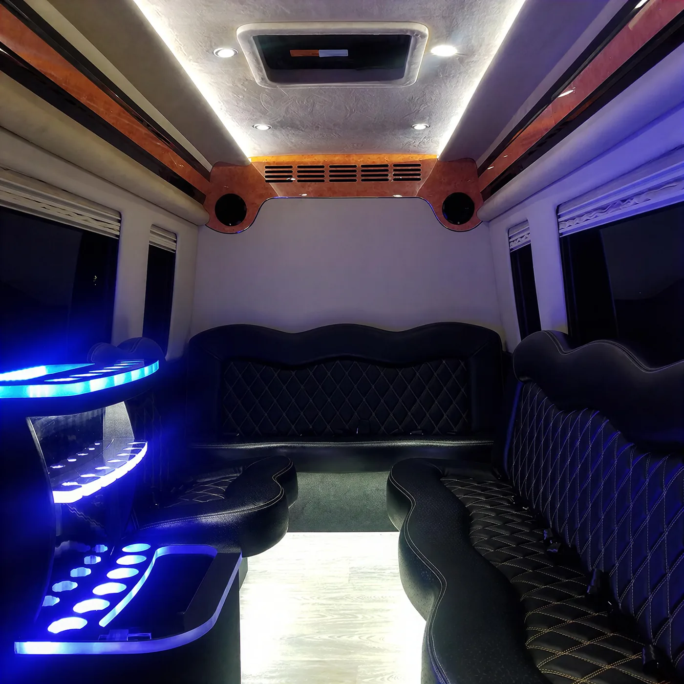 Modern luxury limo bus interior with wraparound seating and LED lighting