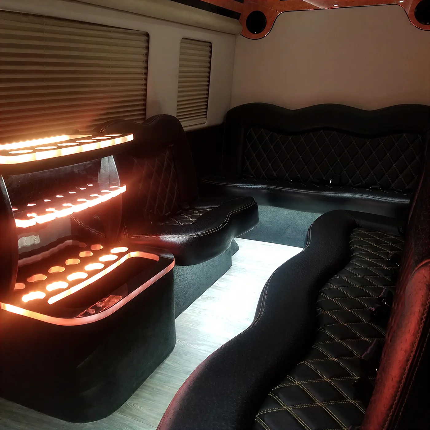 Luxury limo bus interior with illuminated bar shelves and leather seating for group events